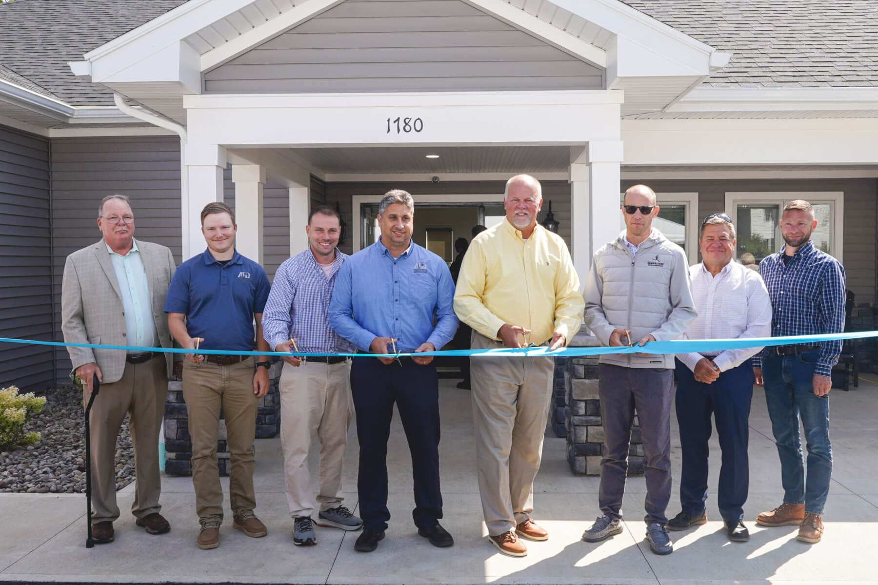Professional headshot of man standing outdoors with a blurred green background.