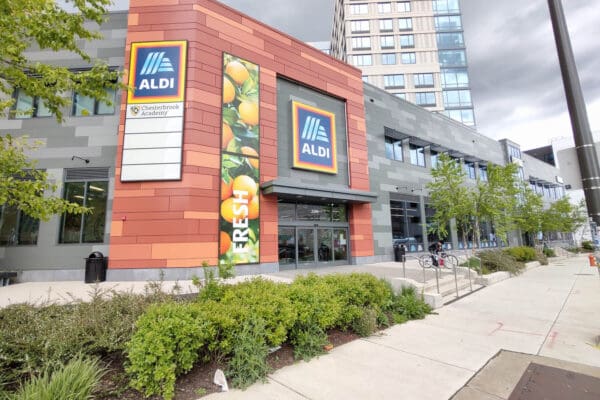 Modern ALDI store entrance highlighting fresh produce in urban setting, showcasing sustainable shopping options.