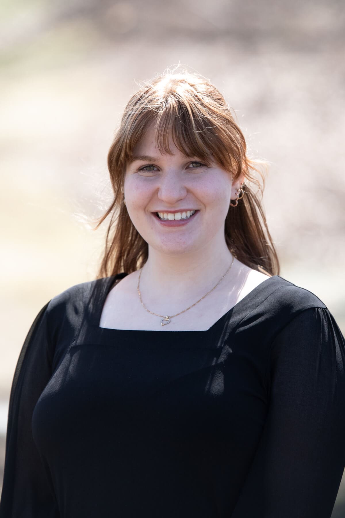 Professional headshot of woman standing outdoors with a blurred background.