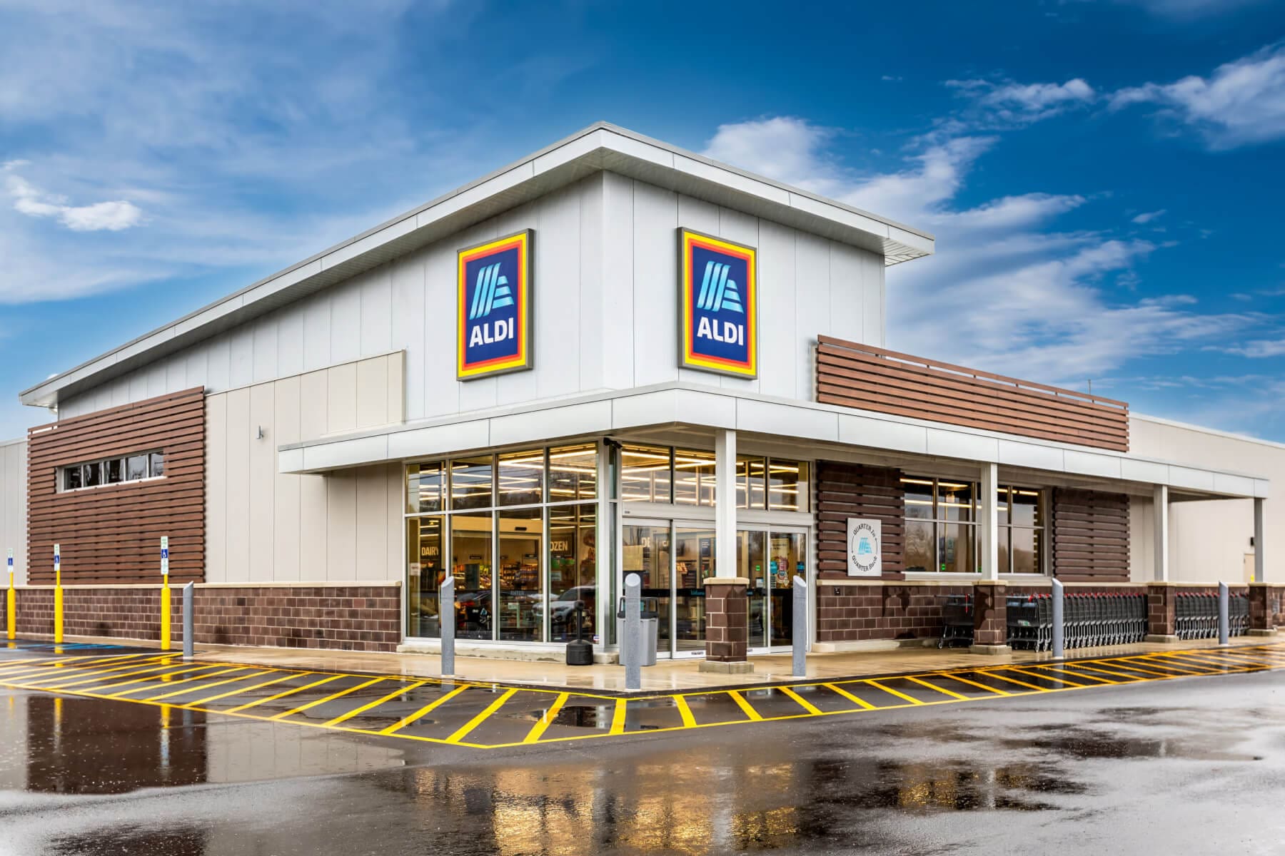 Exterior view of an Aldi supermarket showing the storefront and parking area on a clear day.