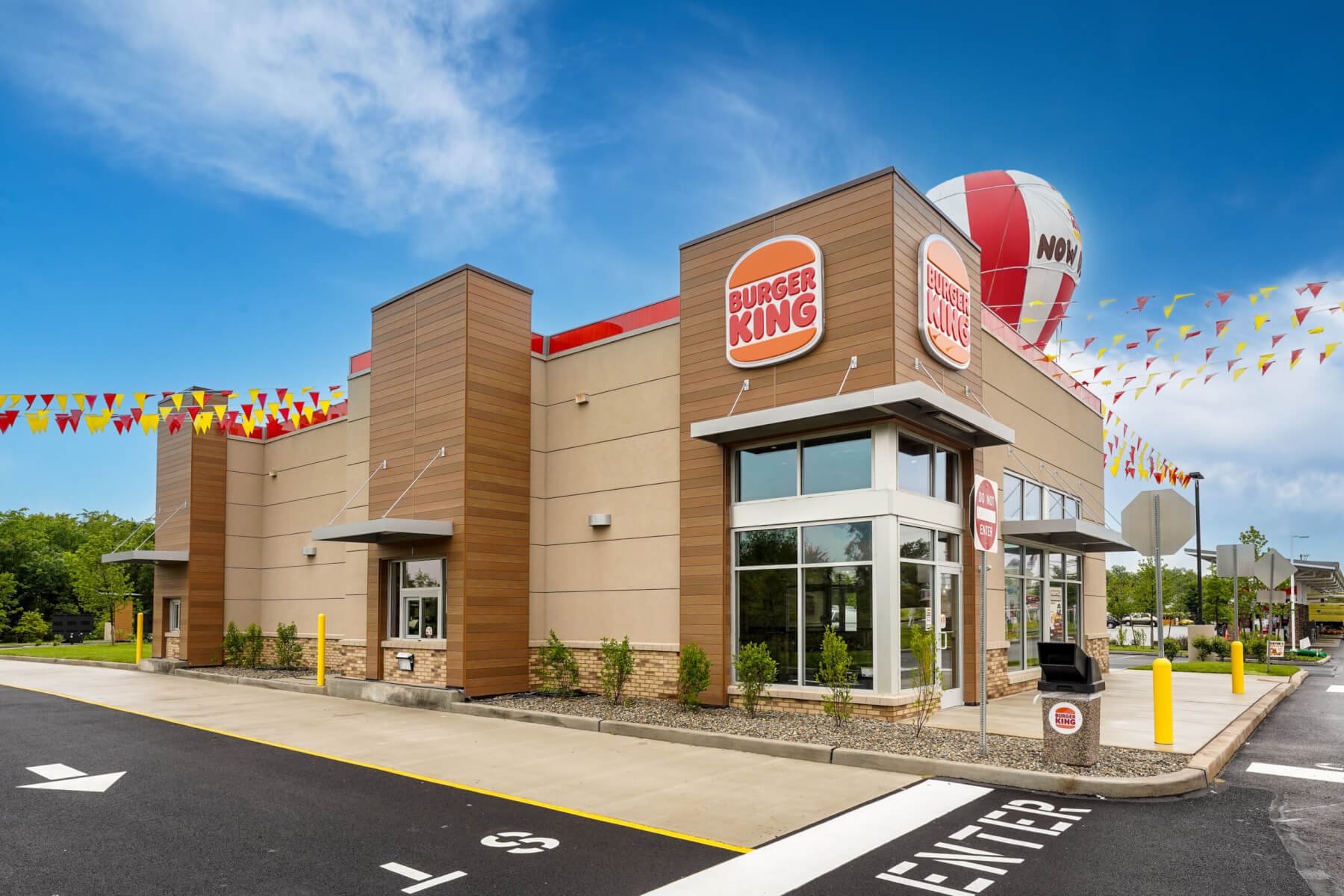 Exterior view of a Burger King restaurant on a clear day, featuring bold signage and festive flags.
