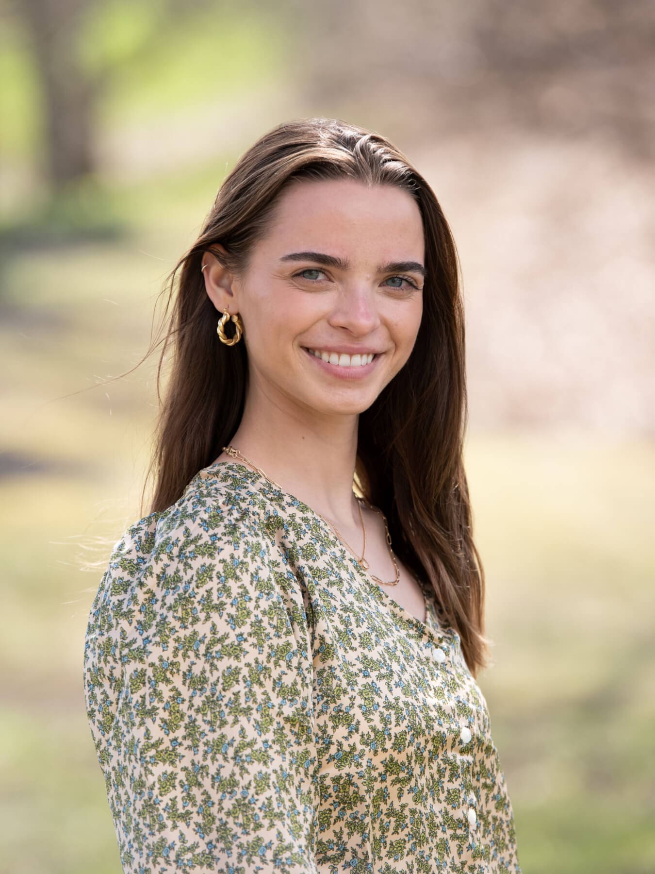 Professional headshot of woman standing outdoors with a blurred background.