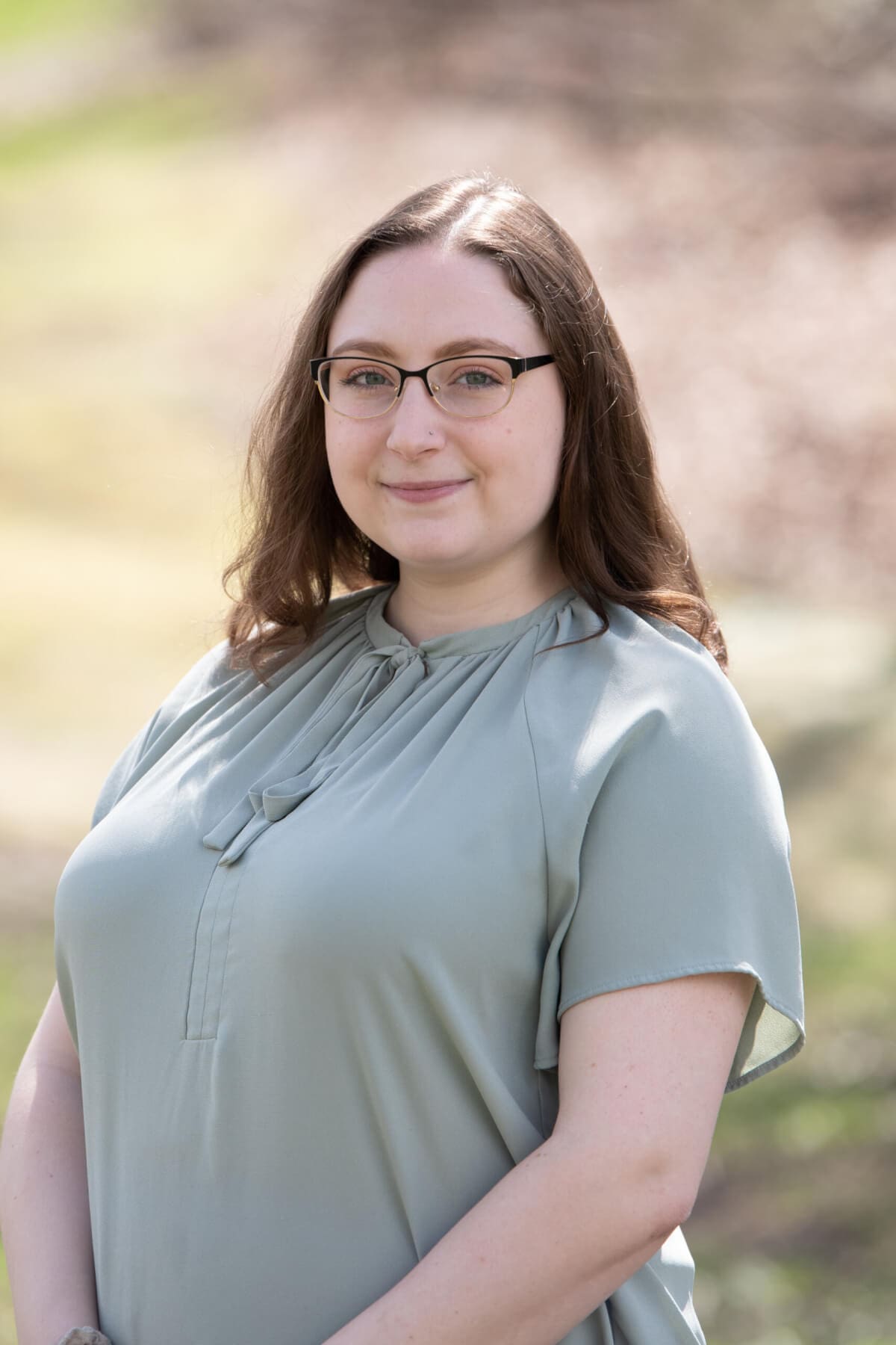 Professional headshot of woman standing outdoors with a blurred background.