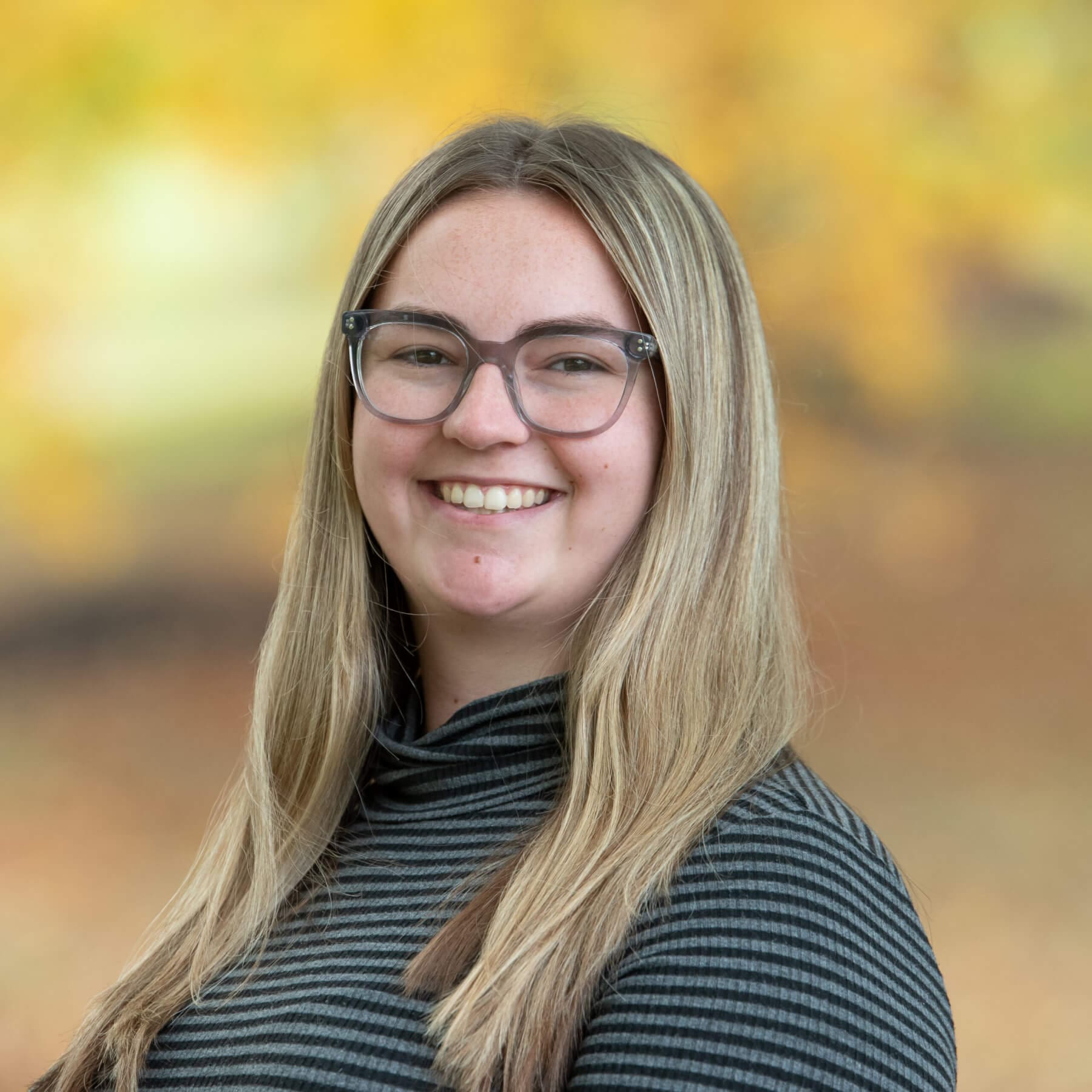 Professional headshot of woman standing outdoors with a blurred background.