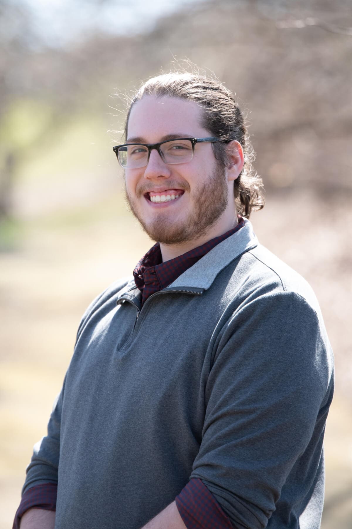 Professional headshot of man standing outdoors with a blurred background.