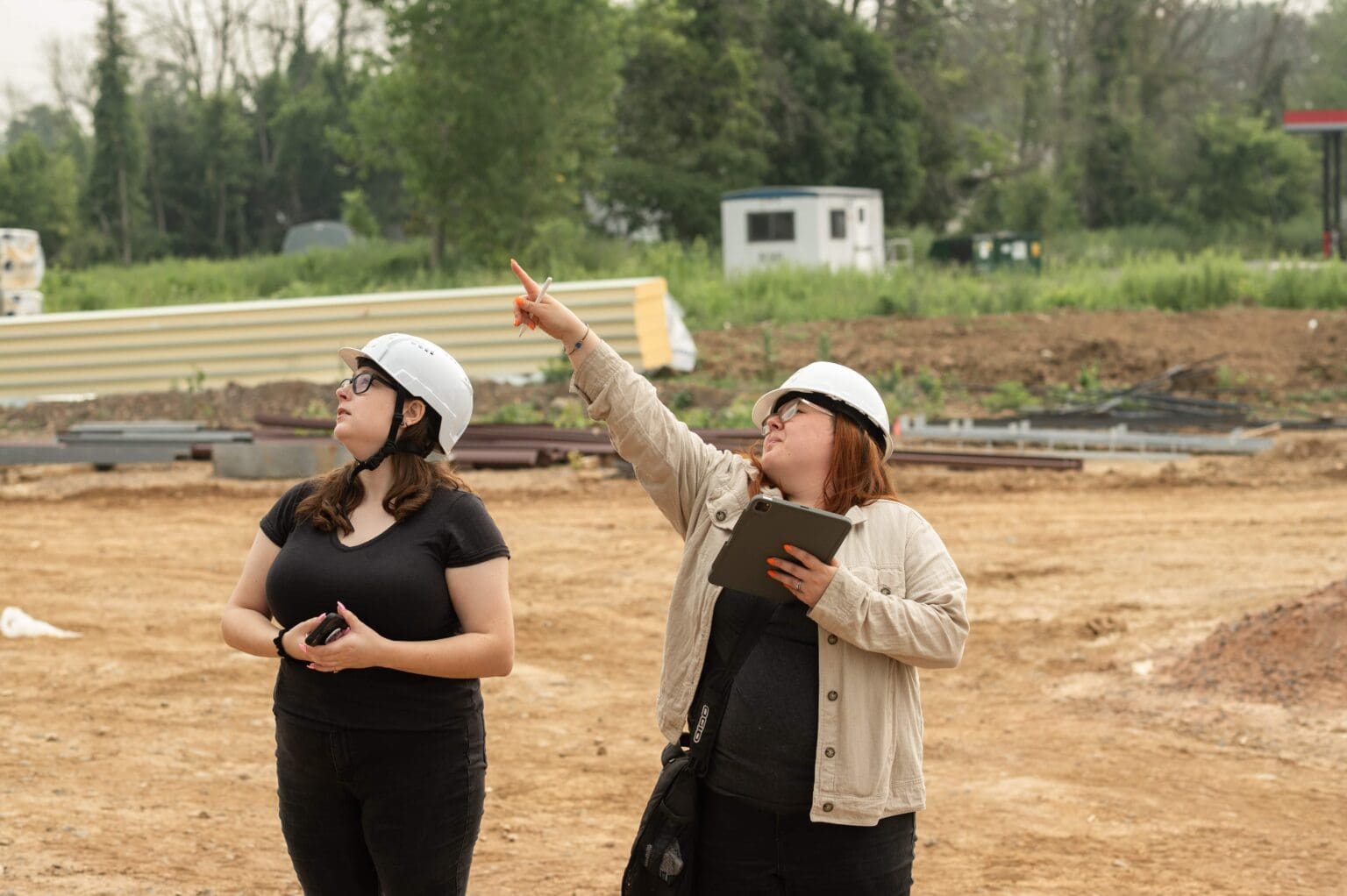 Two women in construction gear discussing site plans at a building site.