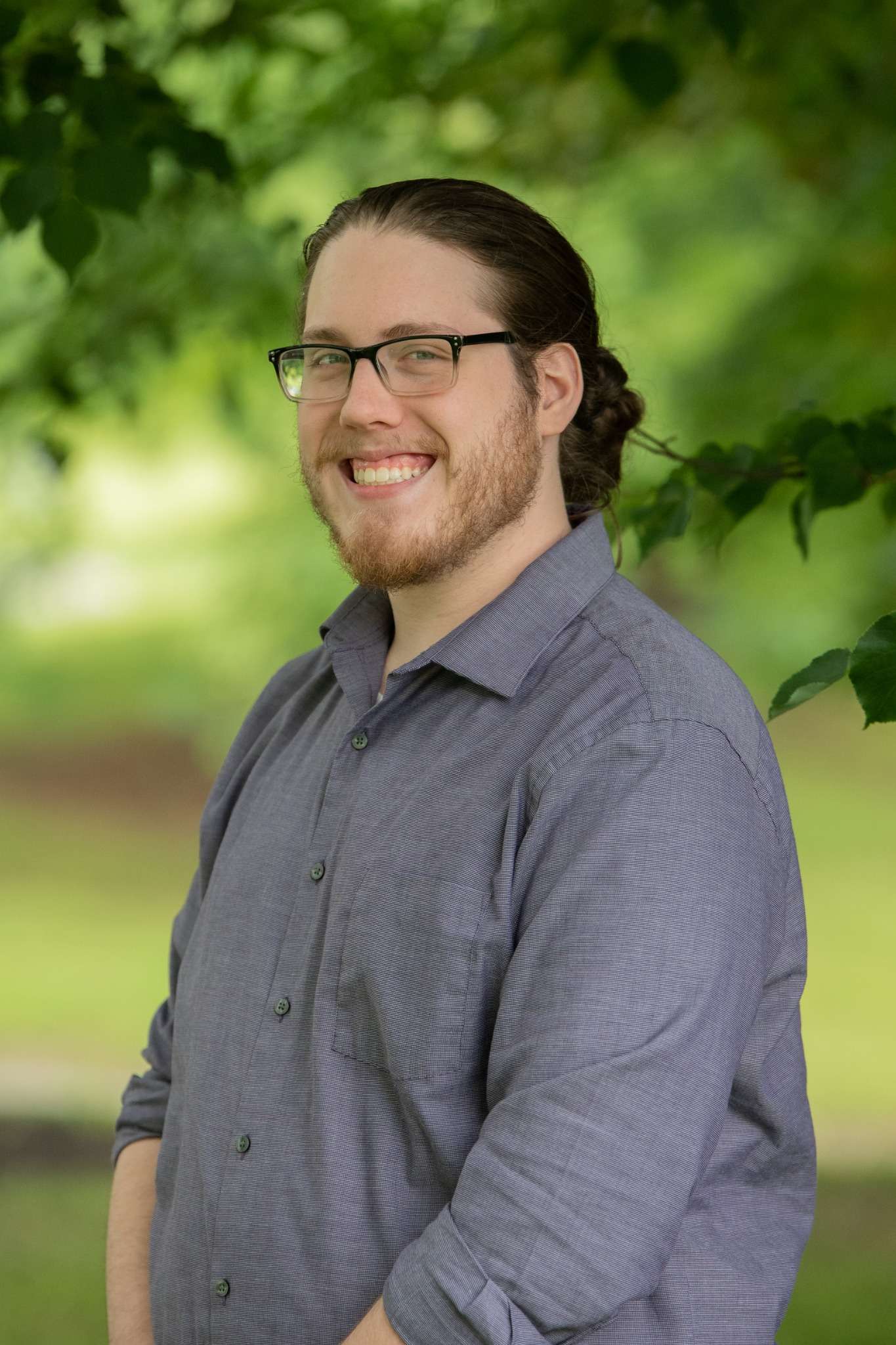 Smiling person in a park setting, representing a friendly and professional team member of [Client/Website Name].