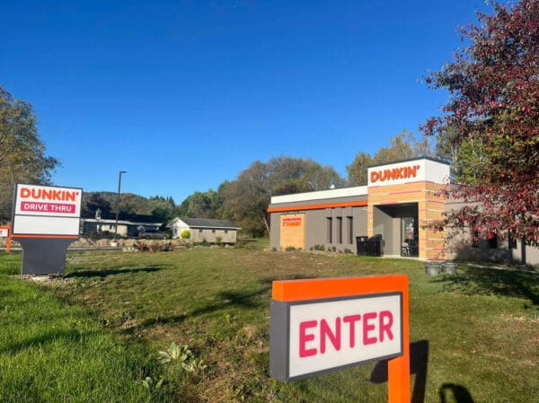 Dunkin' Drive Thru entrance with clear signage surrounded by greenery.
