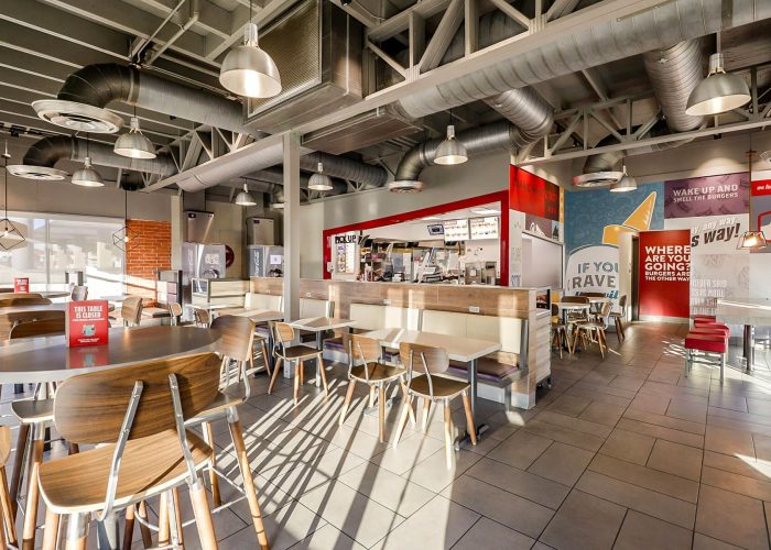 Modern fast food restaurant interior with wooden chairs, tables, and colorful decor.