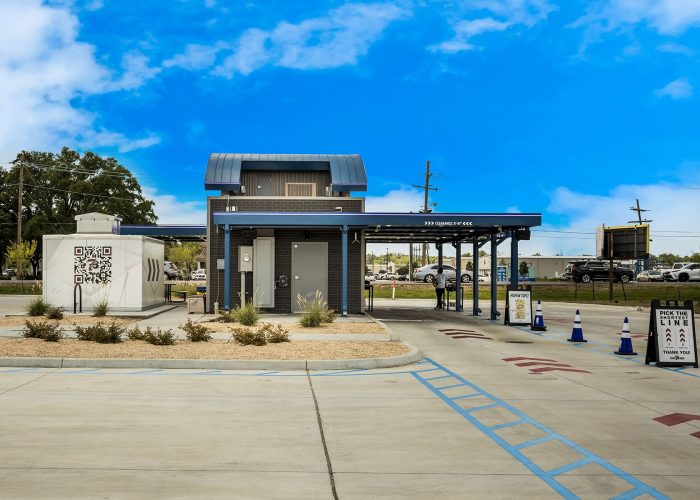 Modern outdoor car wash facility on a sunny day with QR code signage.