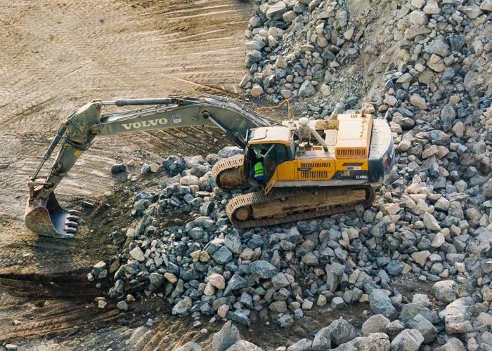 Excavator moving rocks at a quarry, showcasing Volvo construction equipment in action.
