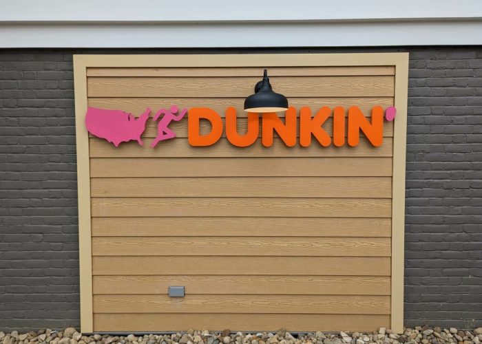 Dunkin' storefront sign featuring a running figure and U.S. map icon.