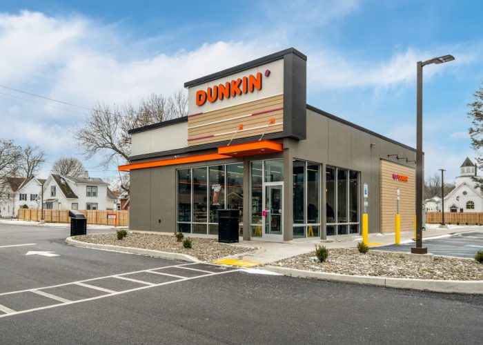 Dunkin' storefront in a suburban area, showcasing its modern design on a clear day.
