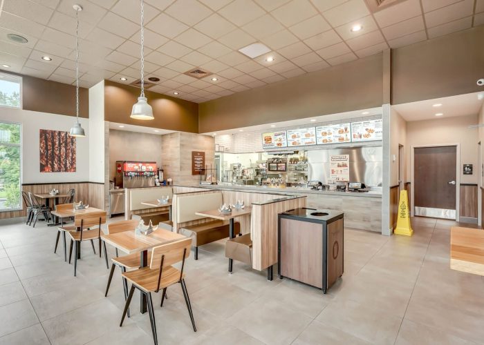 Modern fast-food restaurant interior with seating and counter service area, highlighting clean design.