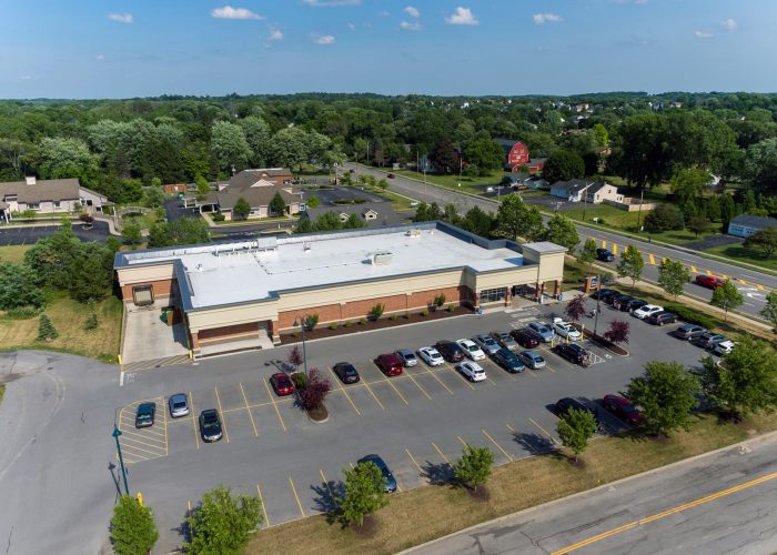 Aerial view of supermarket parking lot on a sunny day near a residential area.
