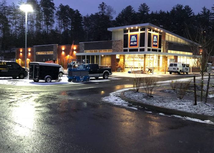 Exterior view of an illuminated Aldi store at dusk, with a snowy parking lot.