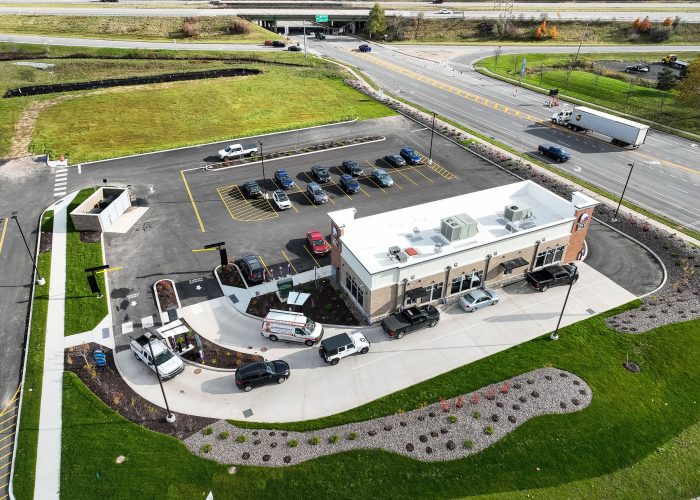 Aerial view of a drive-thru fast food restaurant and parking lot alongside a busy road.