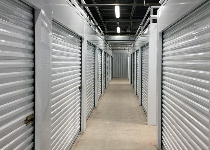 Modern indoor storage units with roll-up doors in a well-lit facility.