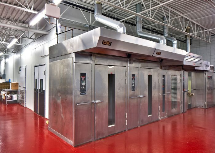 Commercial bakery ovens in a modern facility with red flooring for high-efficiency baking operations.